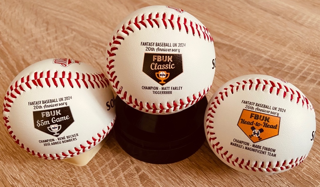 Three printed baseballs displaying league logos and names of champion fantasy managers 2024